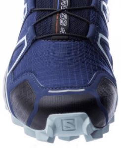 Close-up view of the front of a blue trail running shoe highlighting its robust design, mesh fabric, and branded toe guard, suitable for hiking.