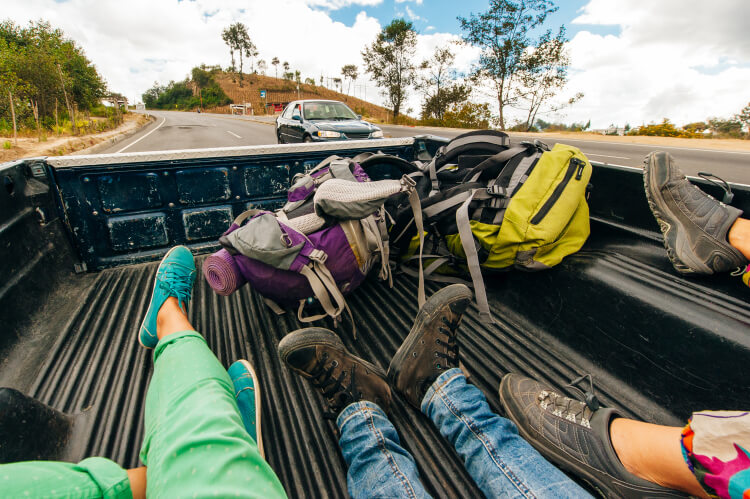 Hikers hitchhiking in back of pickup truck