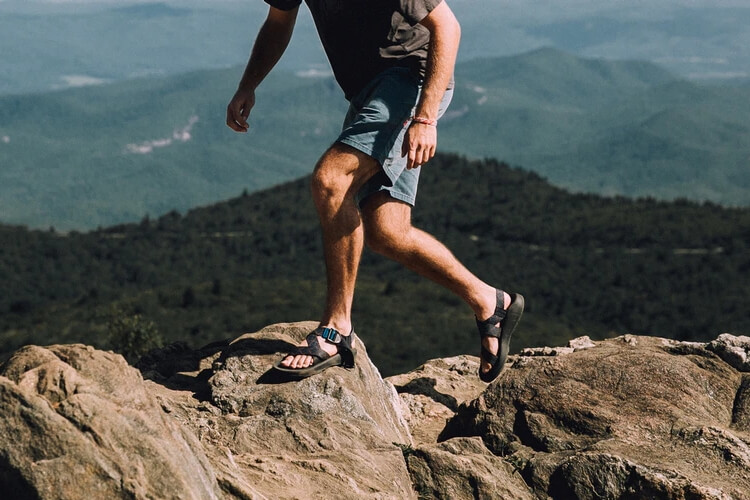 Man wearing Chacos hiking on rocks