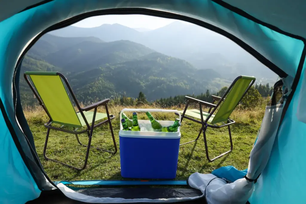 Chairs And Camping Fridge With Bottles Outside The Tent