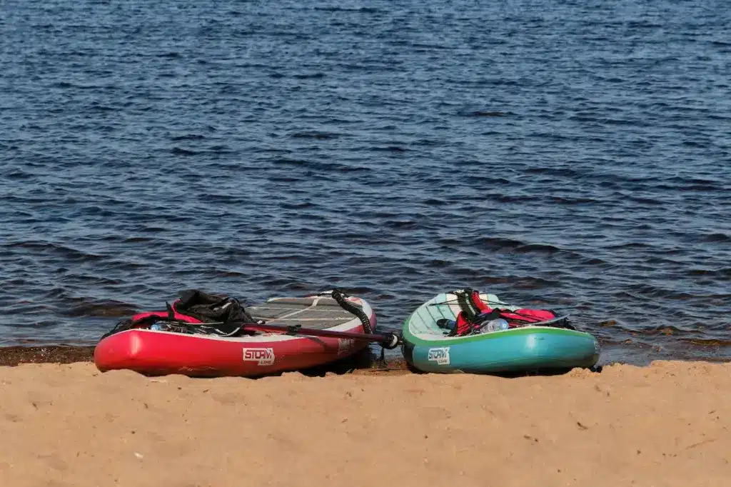 Two Inflatable SUP Lying on Sandy Beach 